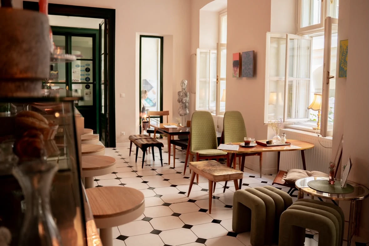 Gemütlicher Innenraum eines Cafés mit Tischen, Stühlen und einem schwarz-weißen Fliesenboden